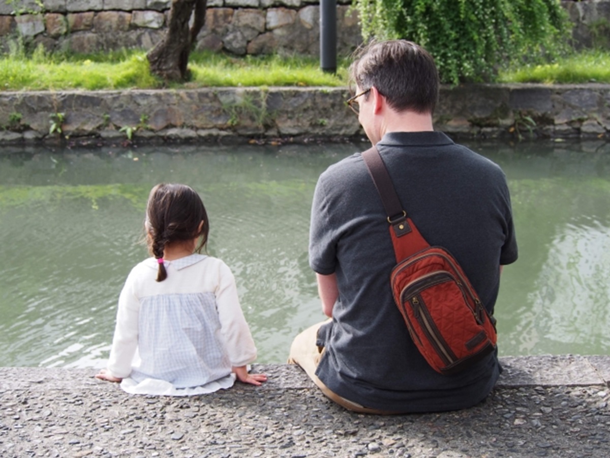 池のほとりに座る父と娘